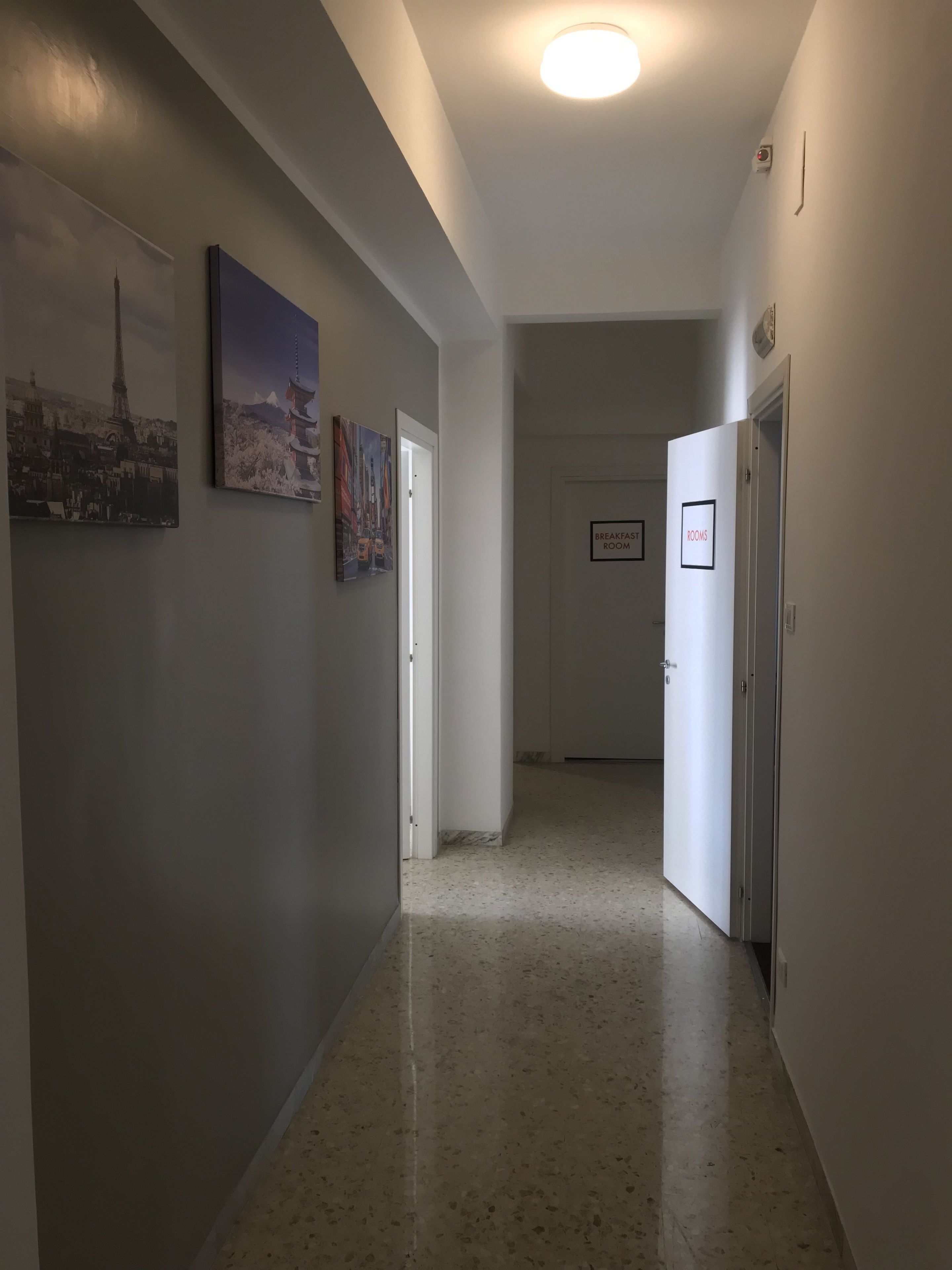 A hallway with a polished floor, a door labeled "Breakfast Room," and two framed pictures on the wall.