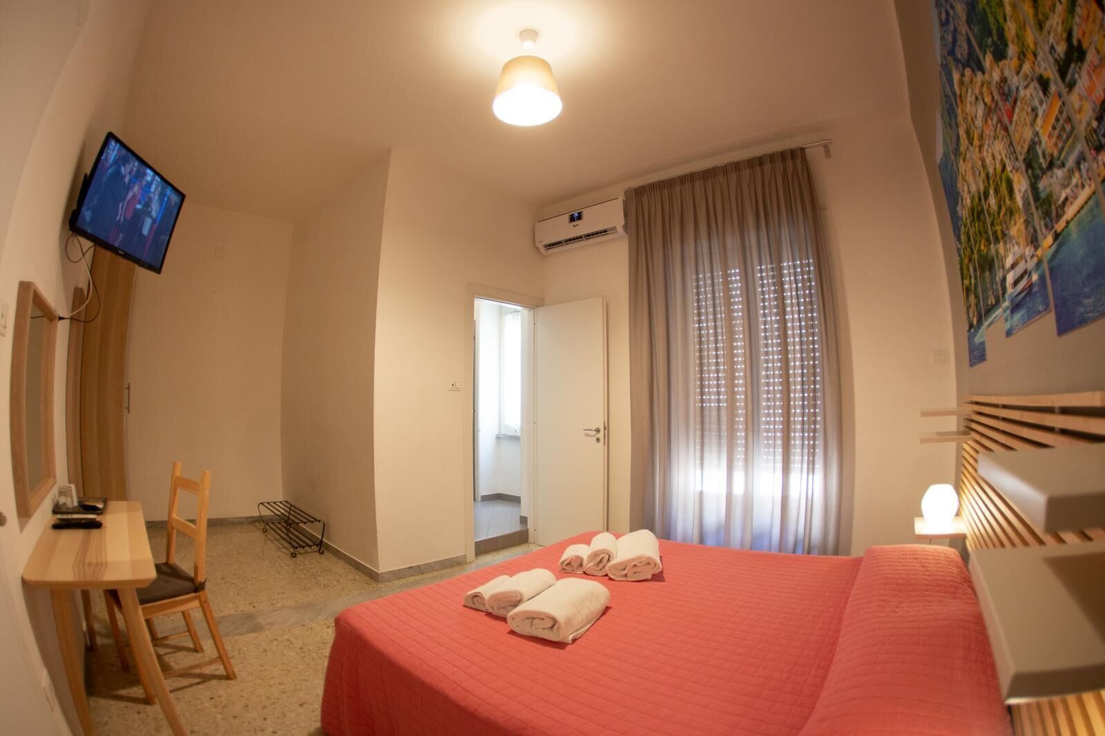 A hotel room with a bed, a desk, a chair, a television, and a window with curtains.