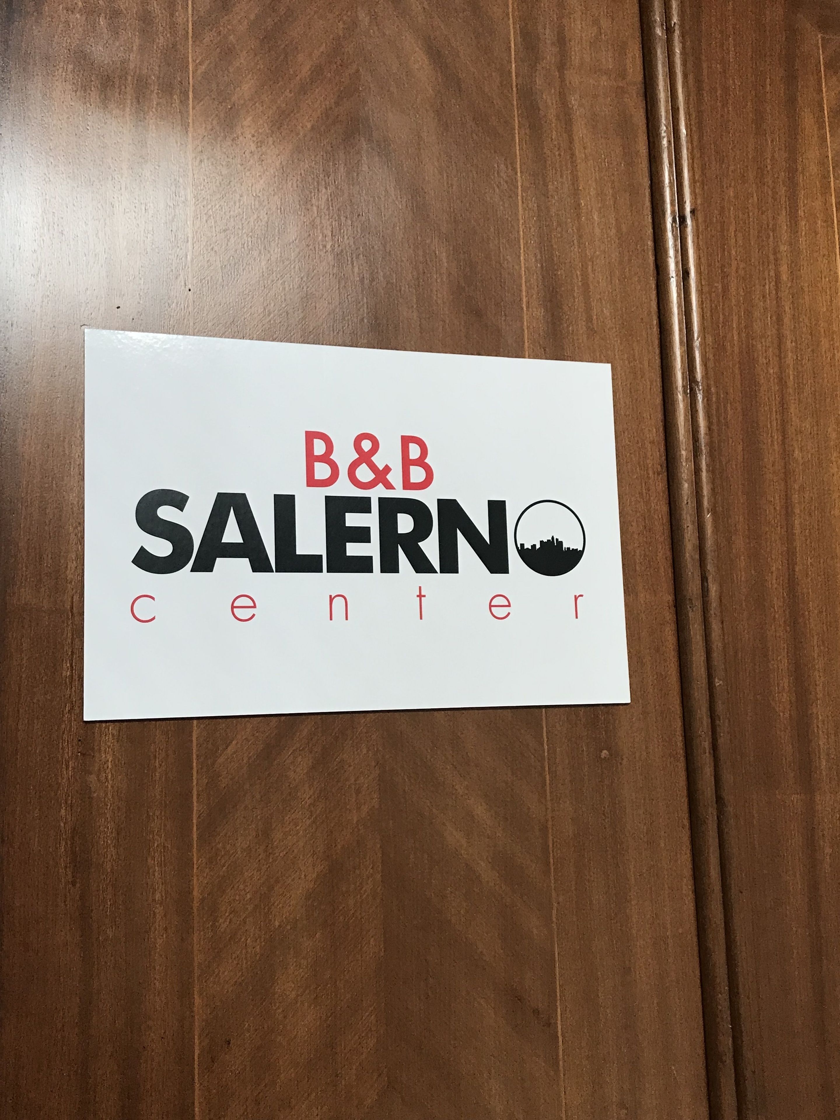 A white sign with the text "B&B SALERN center" on a wooden floor.