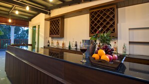 A bar area with a counter, bottles, glasses, and fruits.