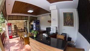 A reception area with a wooden reception desk, a Coca-Cola refrigerator, an ATM, and a computer.