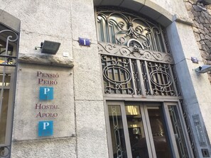 A building with ornate metalwork and a sign indicating 'Pension Peiró Hostal Apollo' with parking signs. - Pensión Peiró (Barcelona)