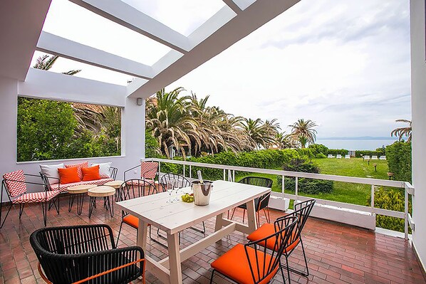 A modern outdoor patio with a white table and chairs, a view of lush greenery and a distant landscape.