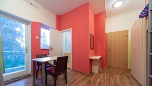 A room with a dining table, chairs, a window, and a door. - Ana Hostel (Ljubljana)