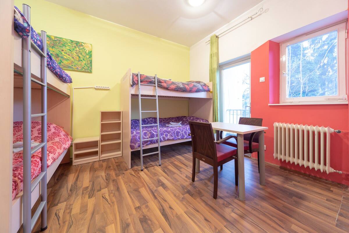 A dormitory room with bunk beds, a desk, and a chair.