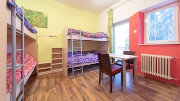A dormitory room with bunk beds, a desk, and a chair.
