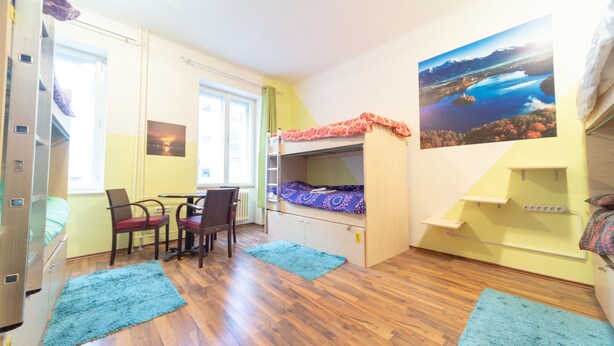 A compact room with a bunk bed, a desk with a chair, a small table, and a window. - Ana Hostel (Ljubljana)