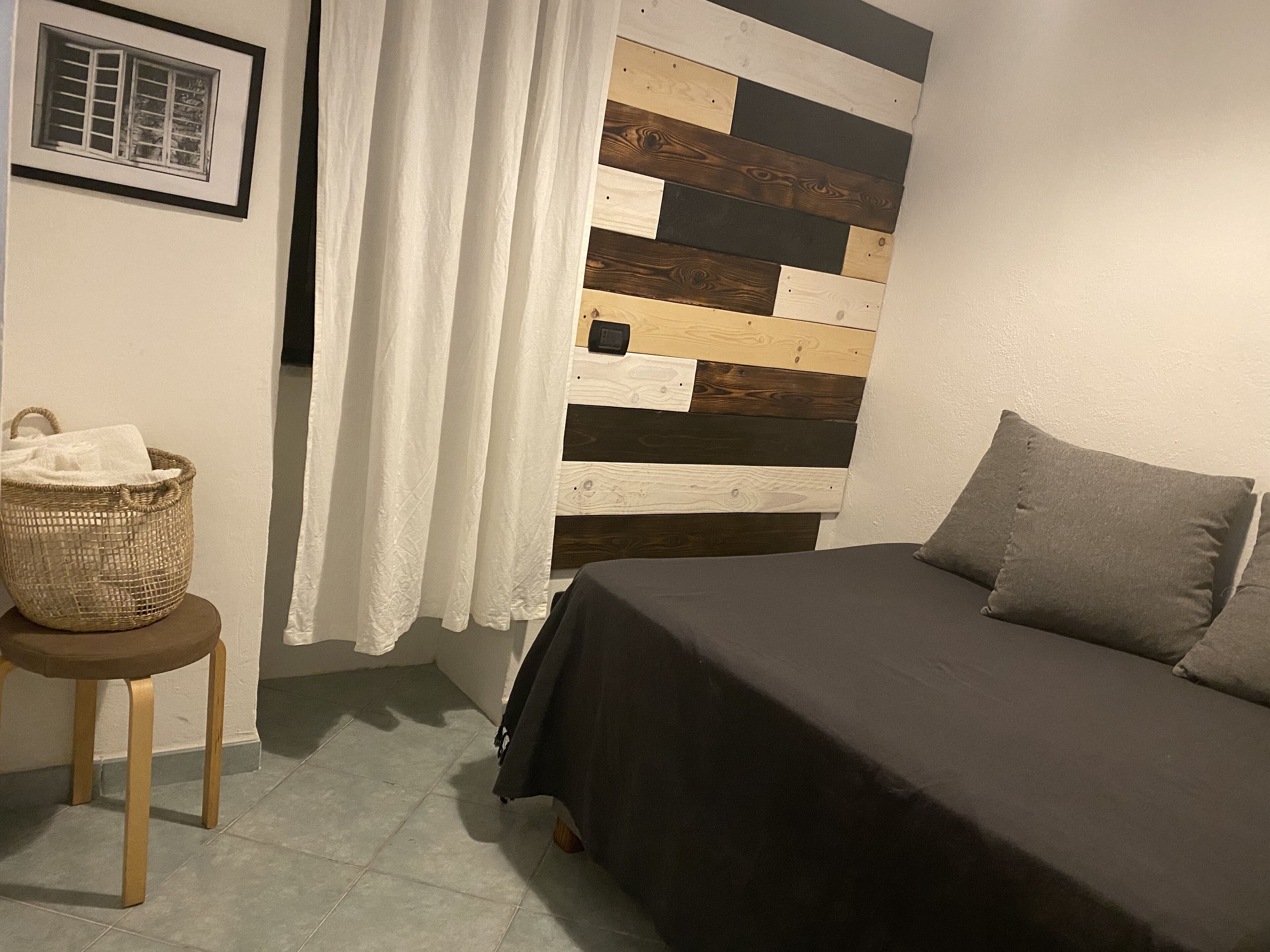A bedroom with a bed, a nightstand, a basket, and a wall with a wooden plank design.