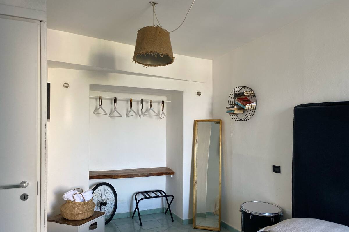 A bedroom with a bed, a dresser, a mirror, a hanging light fixture, and a bicycle.