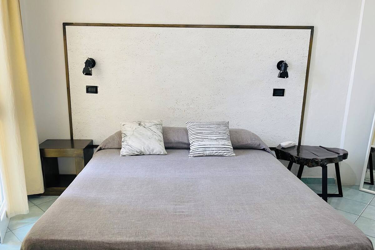A bed with a headboard, two pillows, a bedside table, and a nightstand.