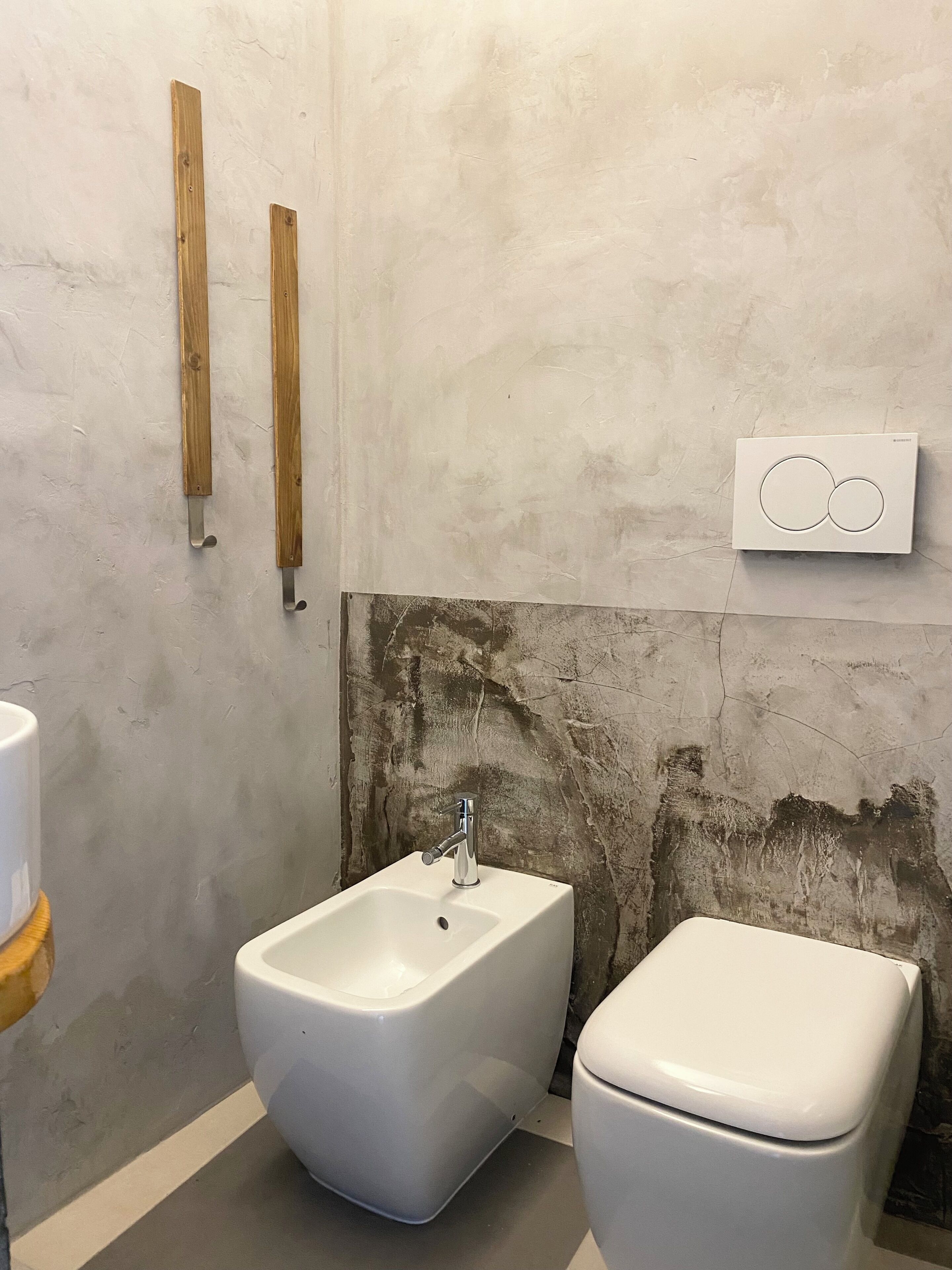 A bathroom with a bidet, a toilet, and wooden handrails.