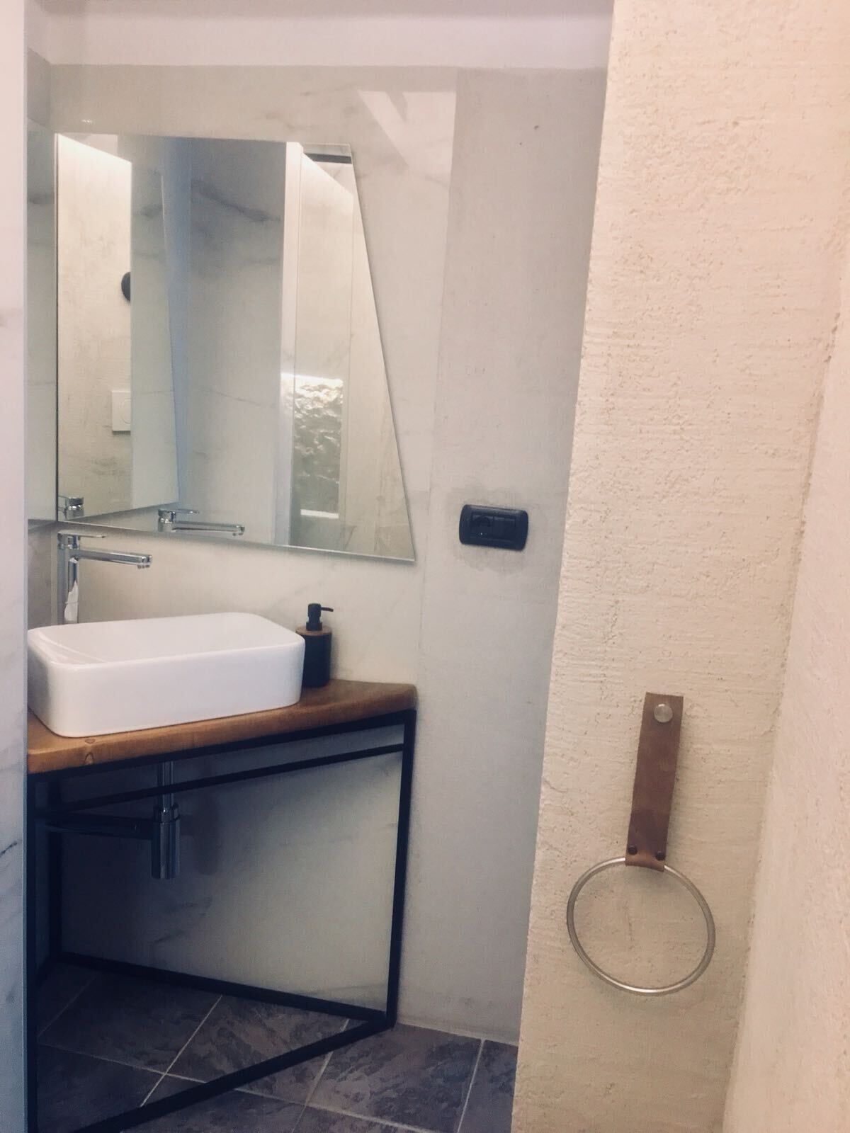 Une salle de bain avec un lavabo blanc, un miroir et un porte-serviettes fixé au mur.