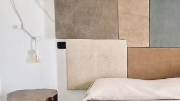 A bedroom with a bed, a nightstand, and a wall-mounted lamp.