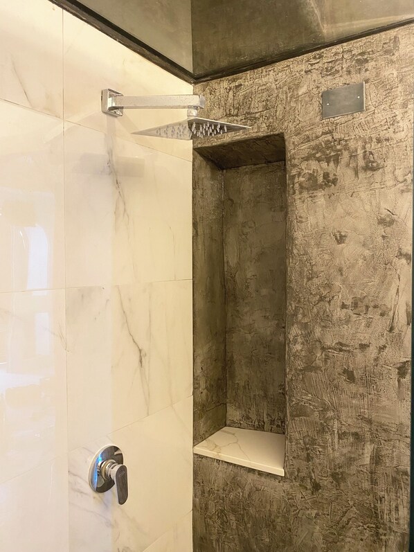 A bathroom with a marble-tiled shower area and a textured wall.