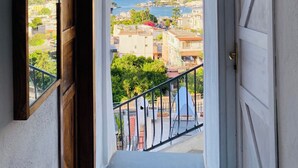 Um corredor com uma porta em arco que dá para uma varanda com vista para uma cidade costeira.