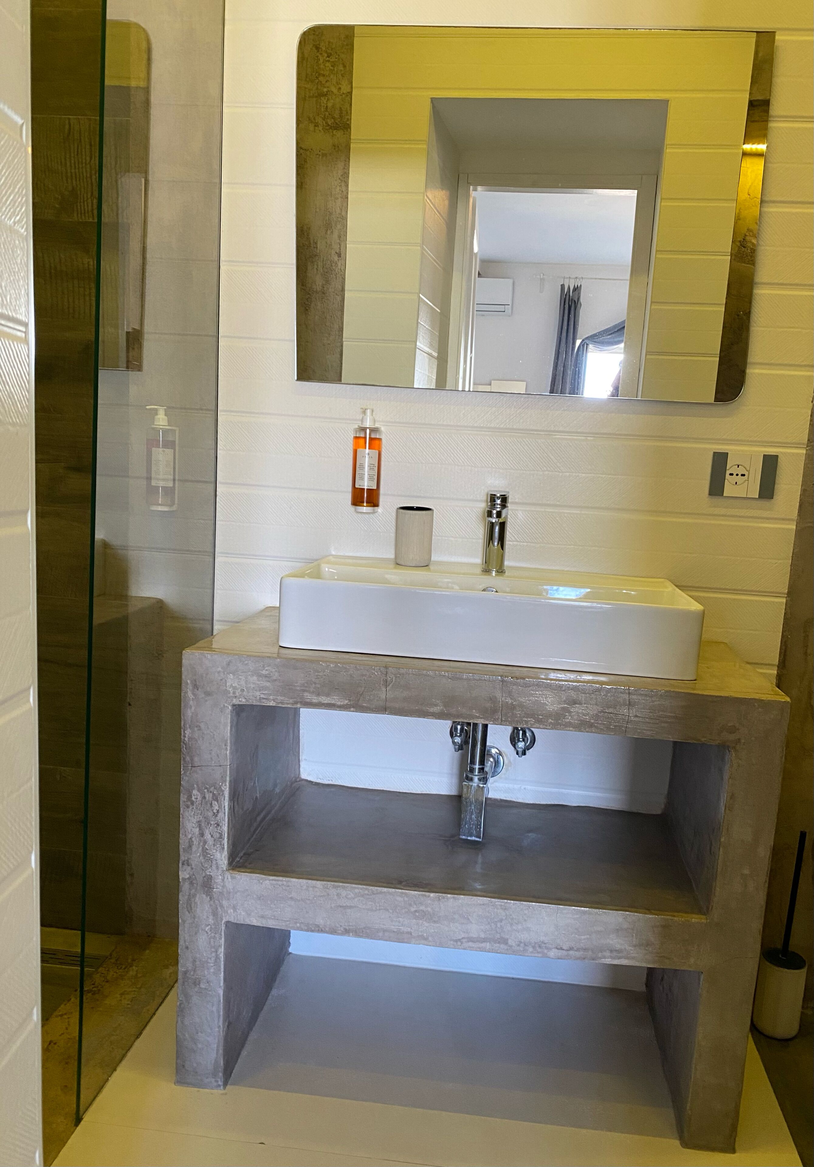 A bathroom with a white sink, a mirror, and a glass shower enclosure.