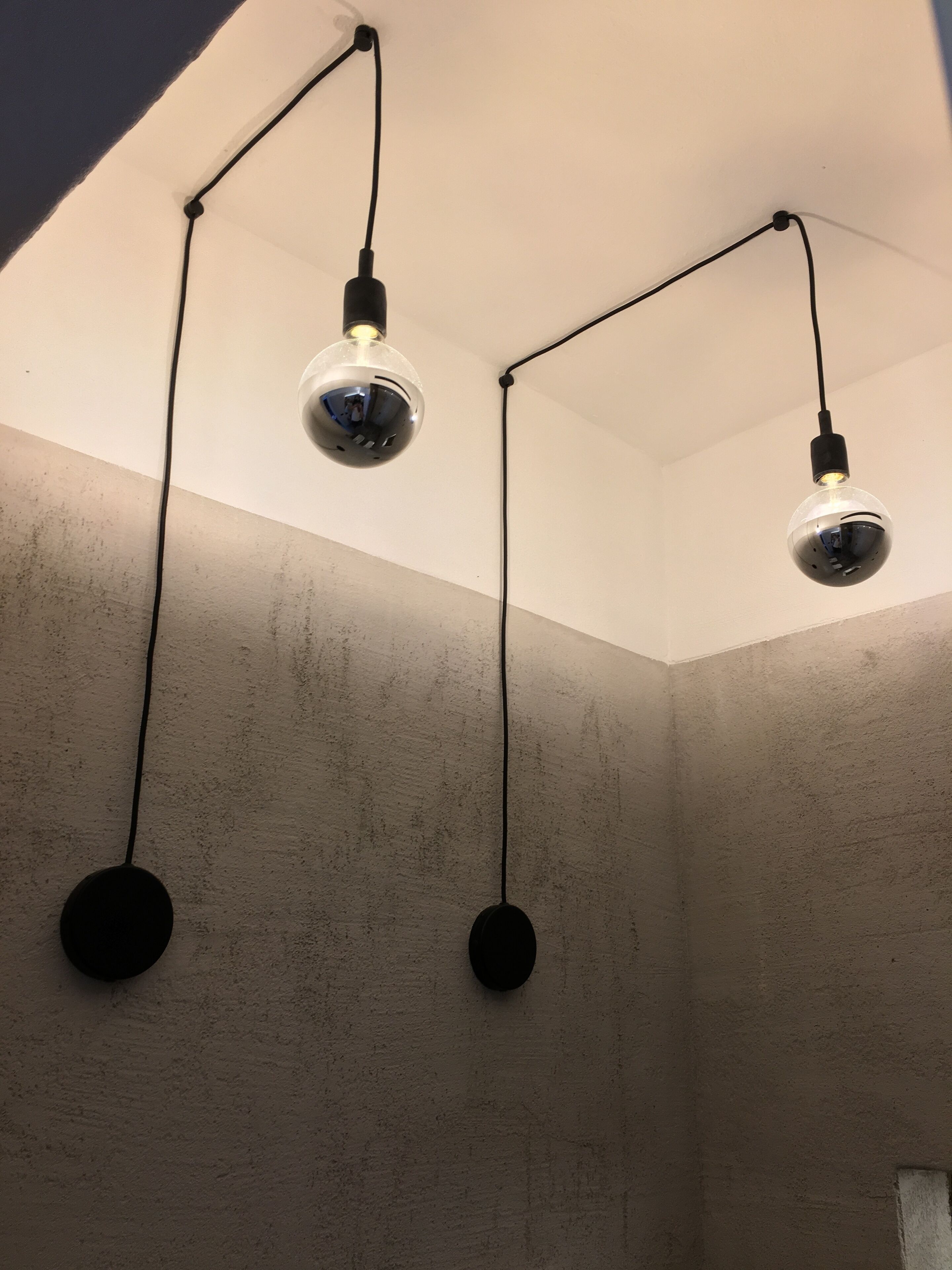 A room with a textured wall and three pendant lights hanging from the ceiling.