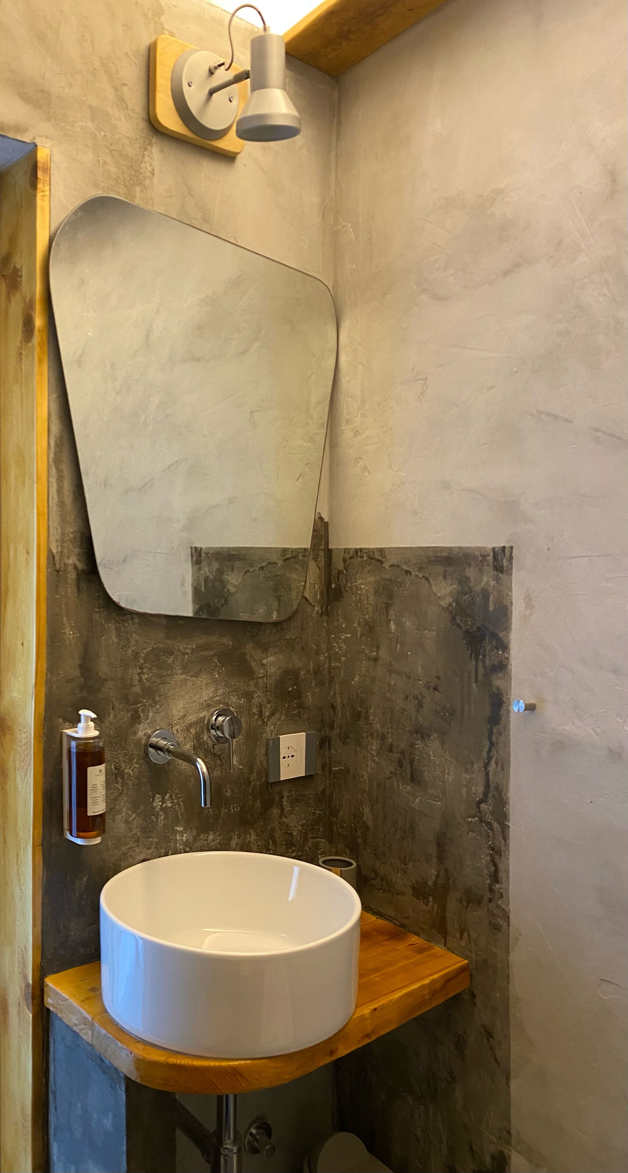 A bathroom with a white sink, wooden countertop, and a large mirror.