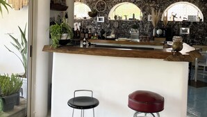 Uma cozinha moderna com painel de fundo de mármore, balcão de madeira e dois banquetas.