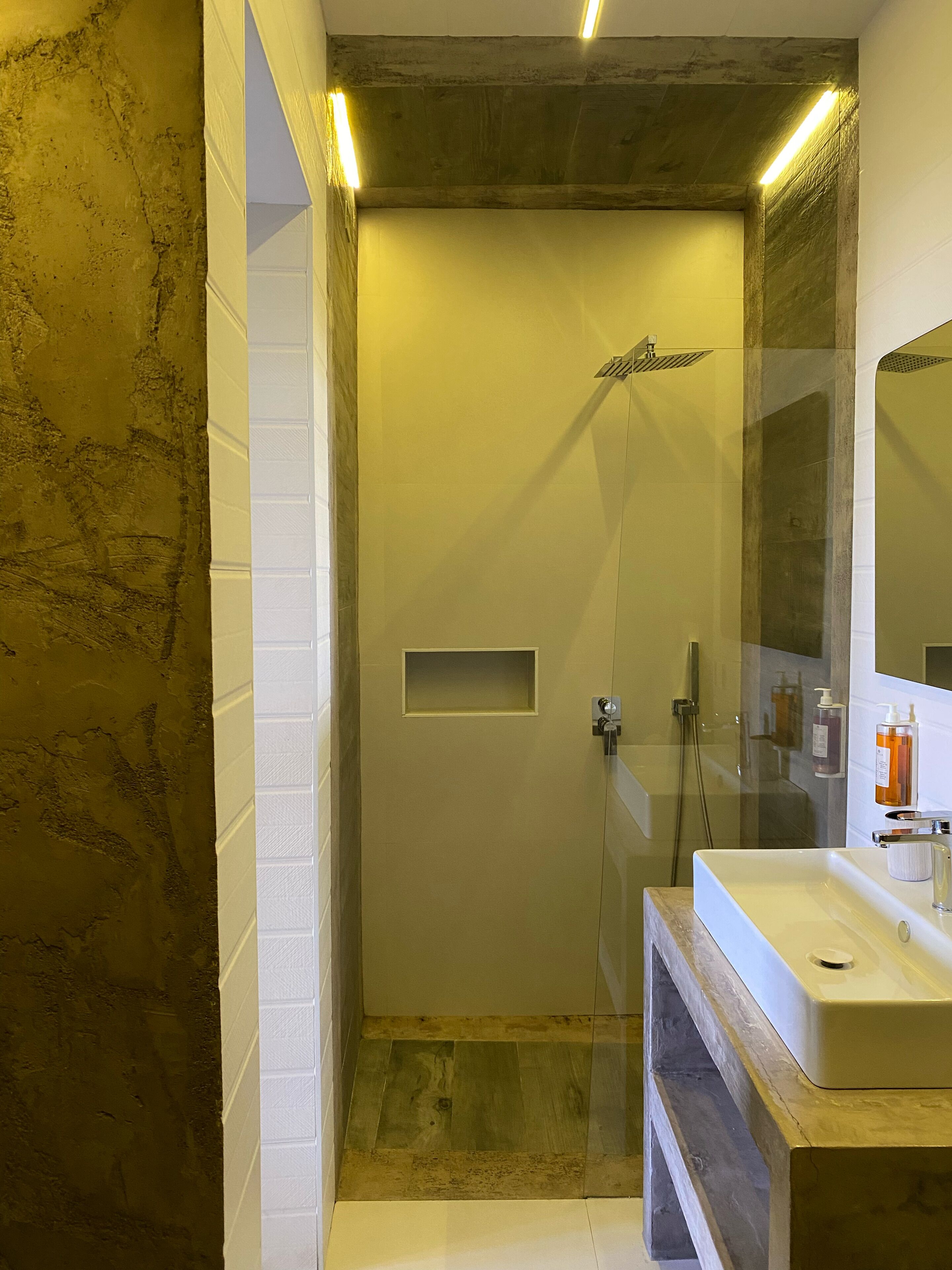 Un baño con ducha, lavamanos y espejo.