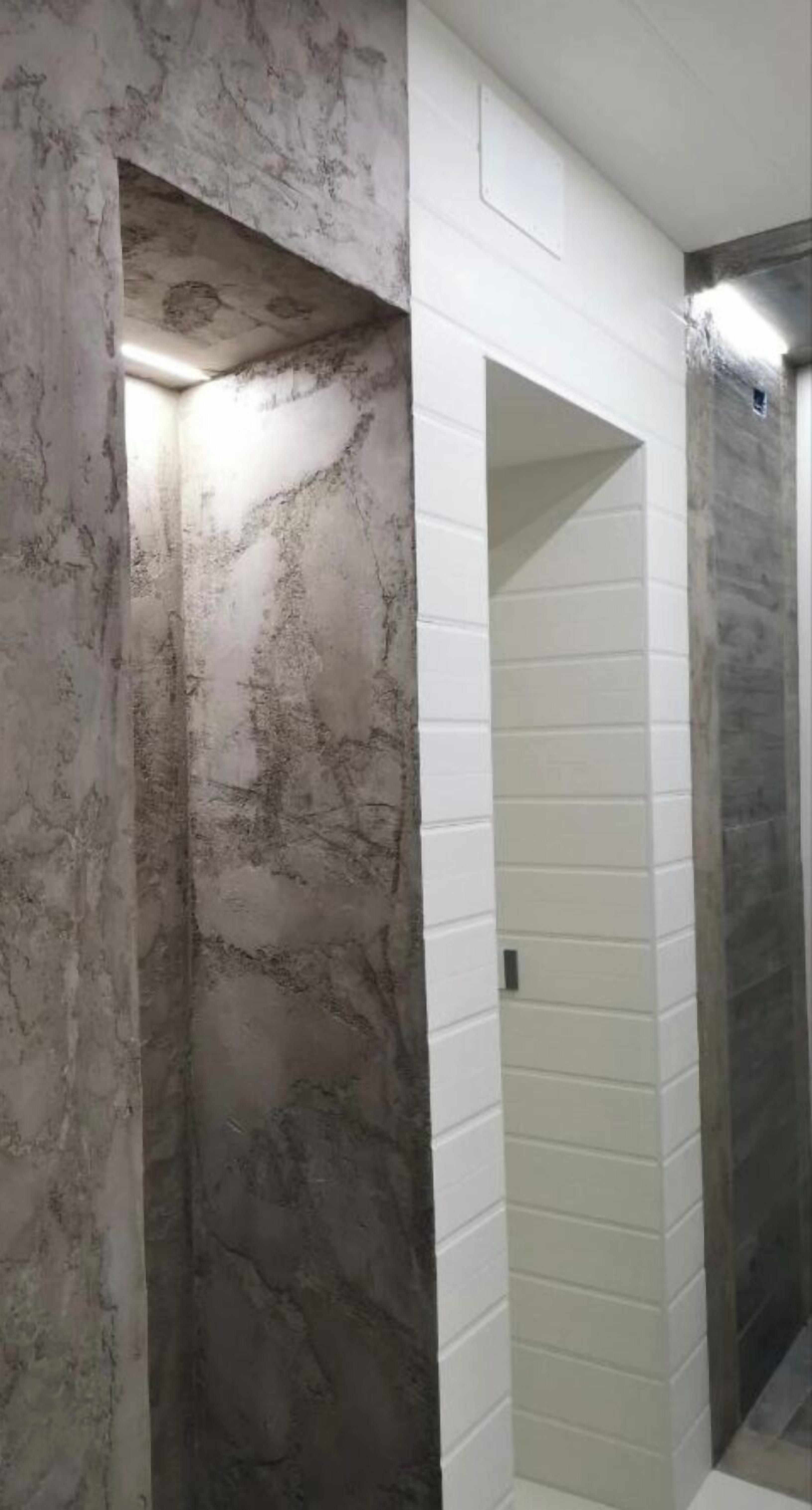 A hallway with marble walls and a white tiled section.