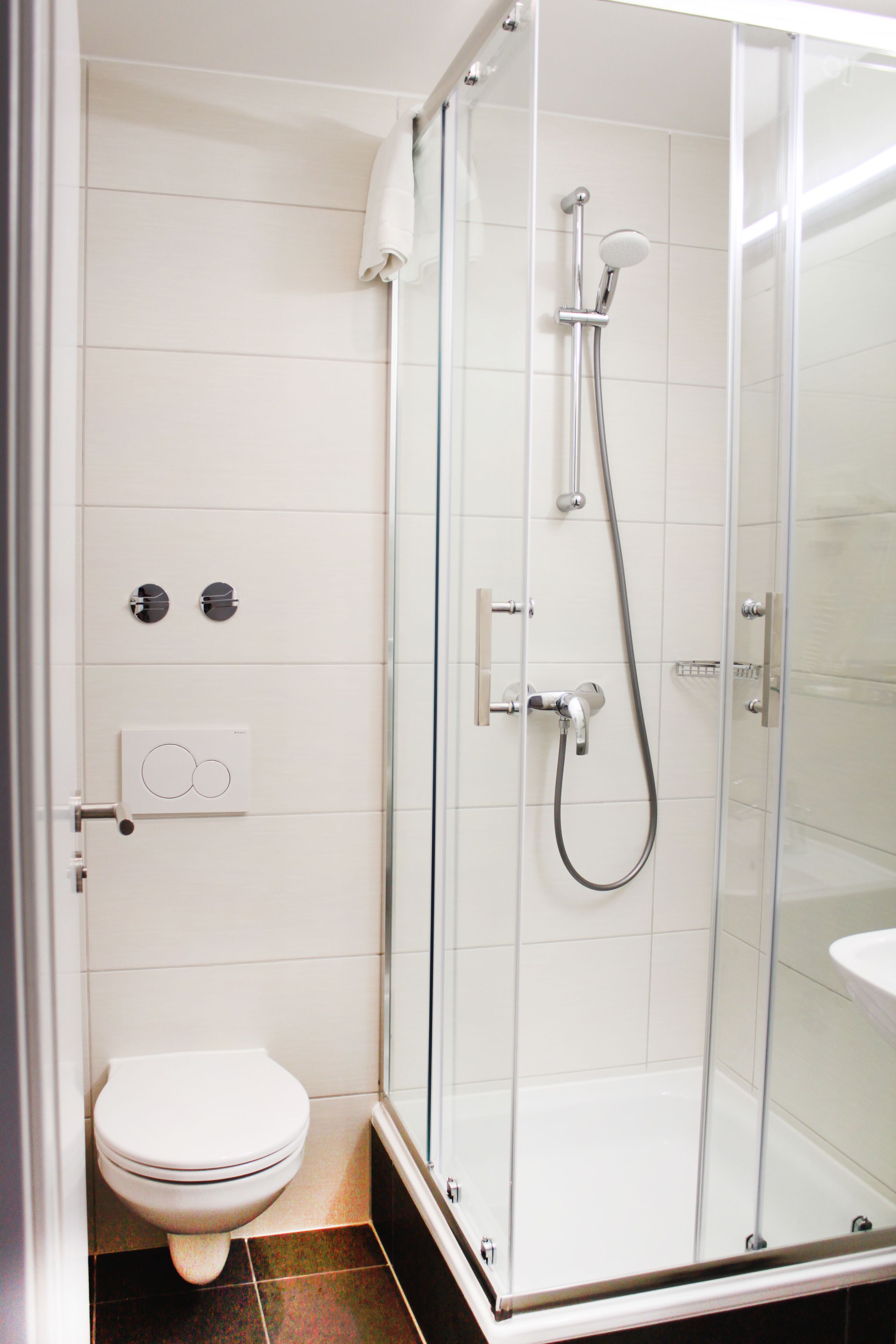 A modern bathroom with a glass-enclosed shower, a toilet, and a wall-mounted control panel.