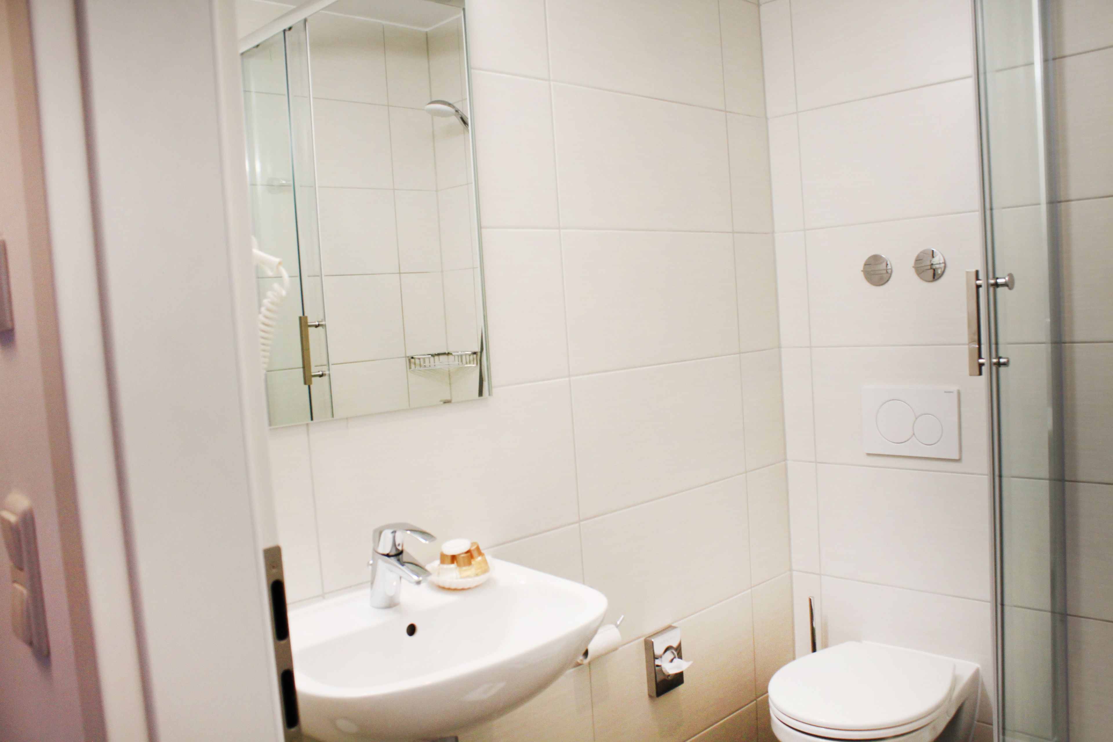 A bathroom with a white sink, mirror, and toilet.
