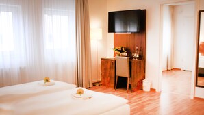 A hotel room with two beds, a desk, a television, and a bathroom visible through an open door. - Anor Hotel I Park Sleep & Fly I Frankfurt Airport (Moerfelden-Walldorf)