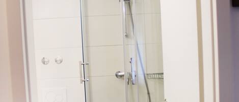A glass-enclosed shower stall with a white toilet and a towel on the floor.
