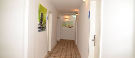 A hallway with a checkered floor, white walls, and a door at the end.