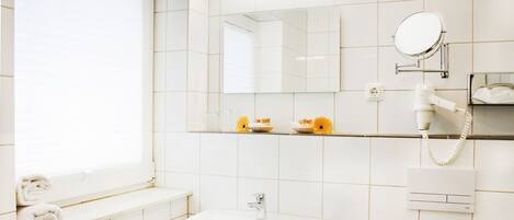 A bathroom with a sink, mirror, towel rack, and a shelf with toiletries.