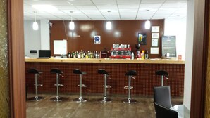 Zona de bar con mostrador, taburetes y máquina de café.