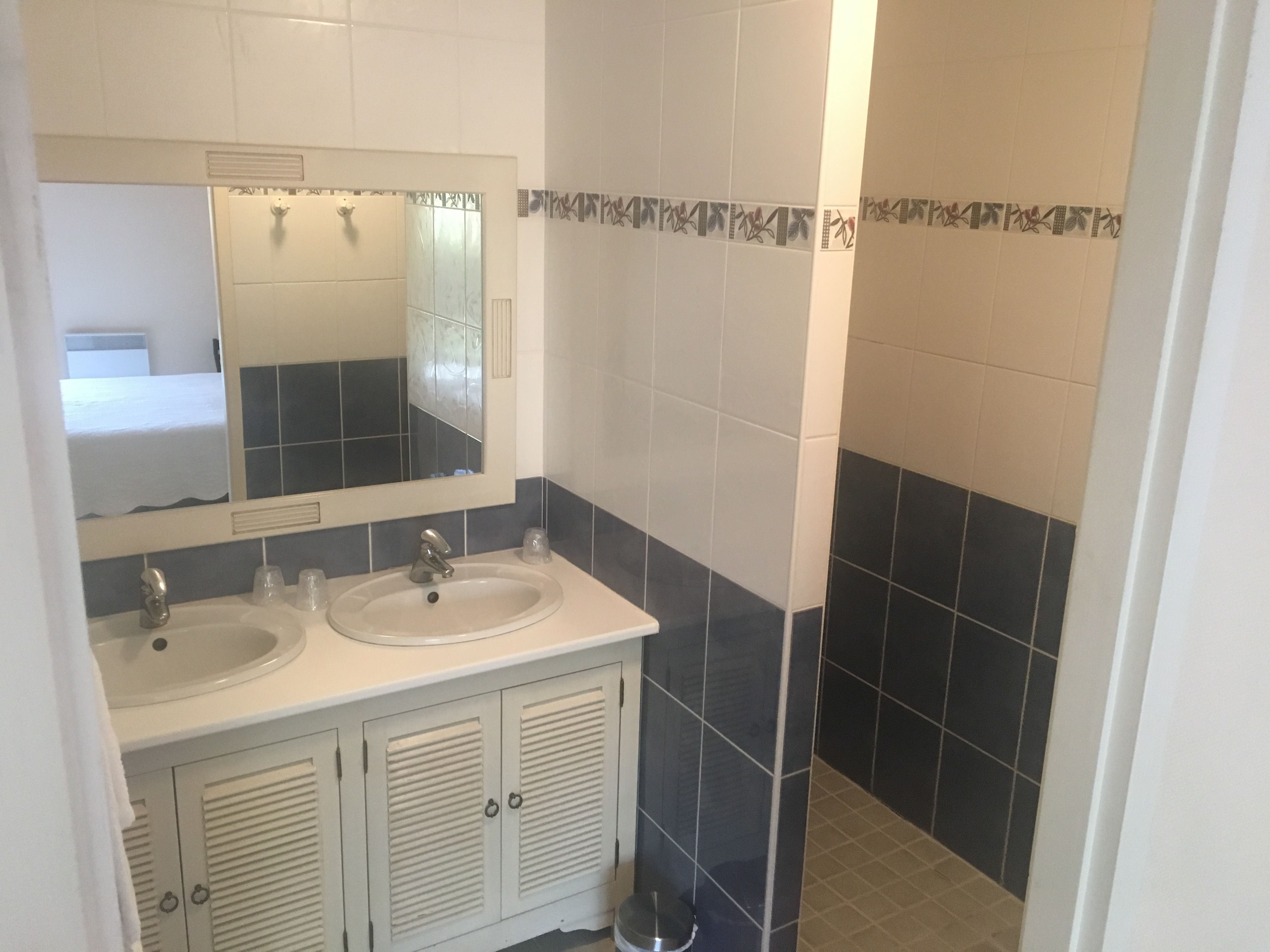 Een badkamer met twee wasbakken, een spiegel en een douche.