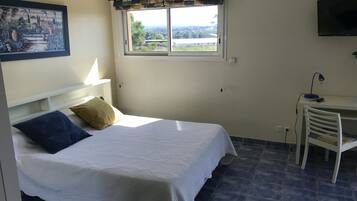 Ein Schlafzimmer mit Bett, Schreibtisch und Fenster mit Blick.