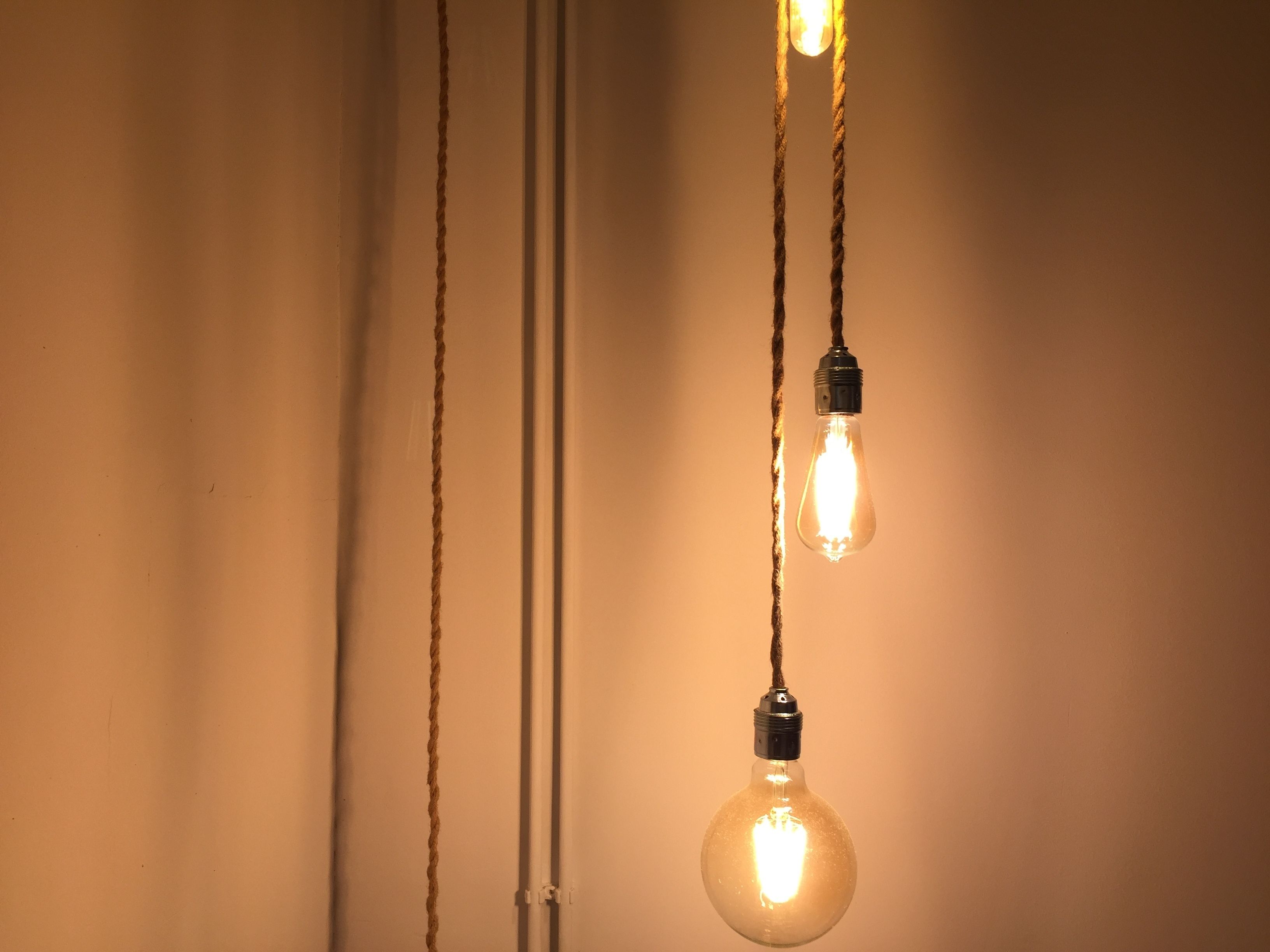 Three light bulbs hanging from a ceiling with visible cables.
