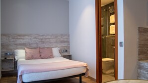 A modern bedroom with a wooden headboard, a large bed with a pink blanket, a bedside table, and a wooden floor. - Hostal Apolo (Barcelona)