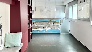 A modern hallway with a red bookshelf, a map mural, and a bench. - Hostal Apolo (Barcelona)