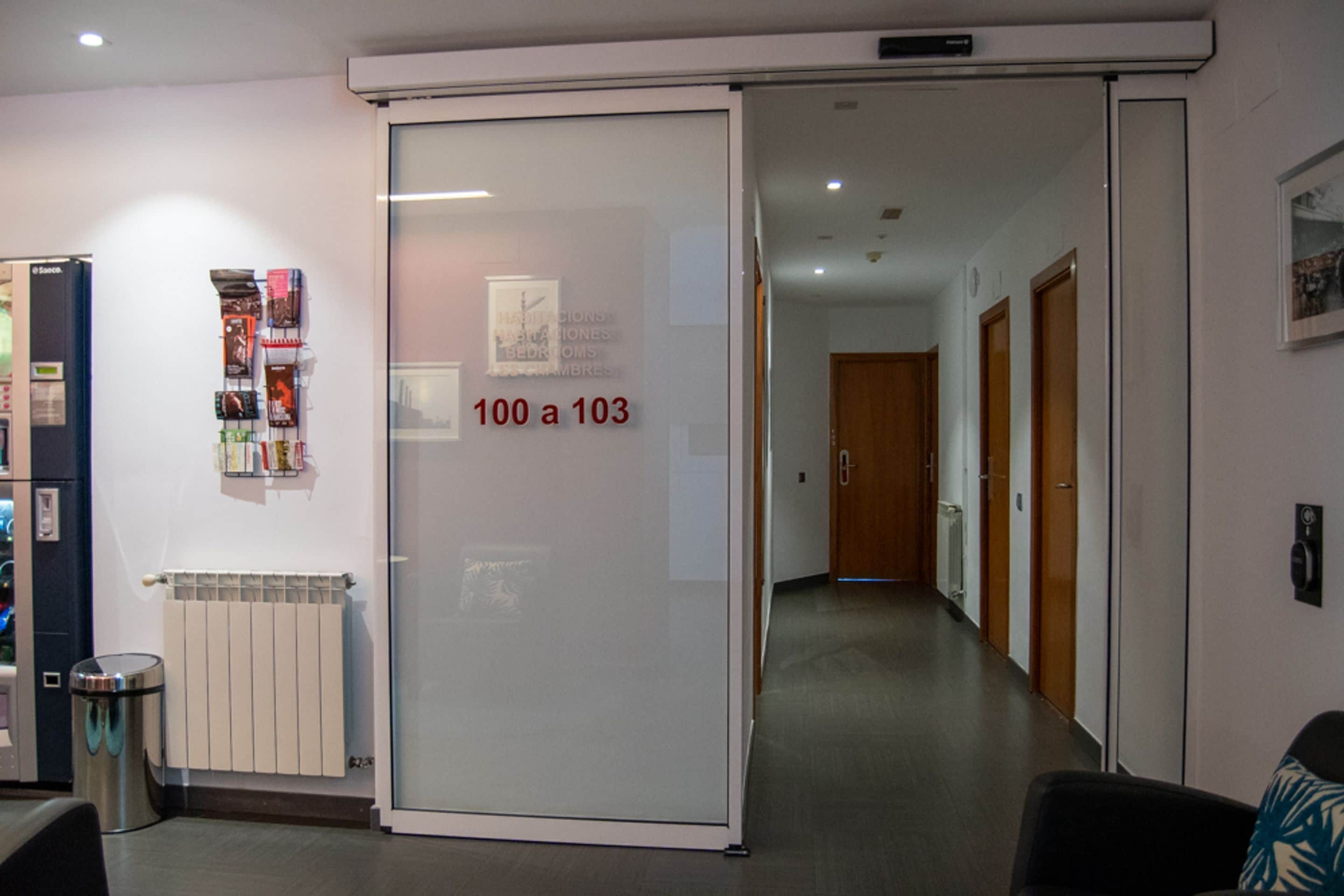 Pasillo de hotel con una puerta corredera que indica los números del 100 al 103.