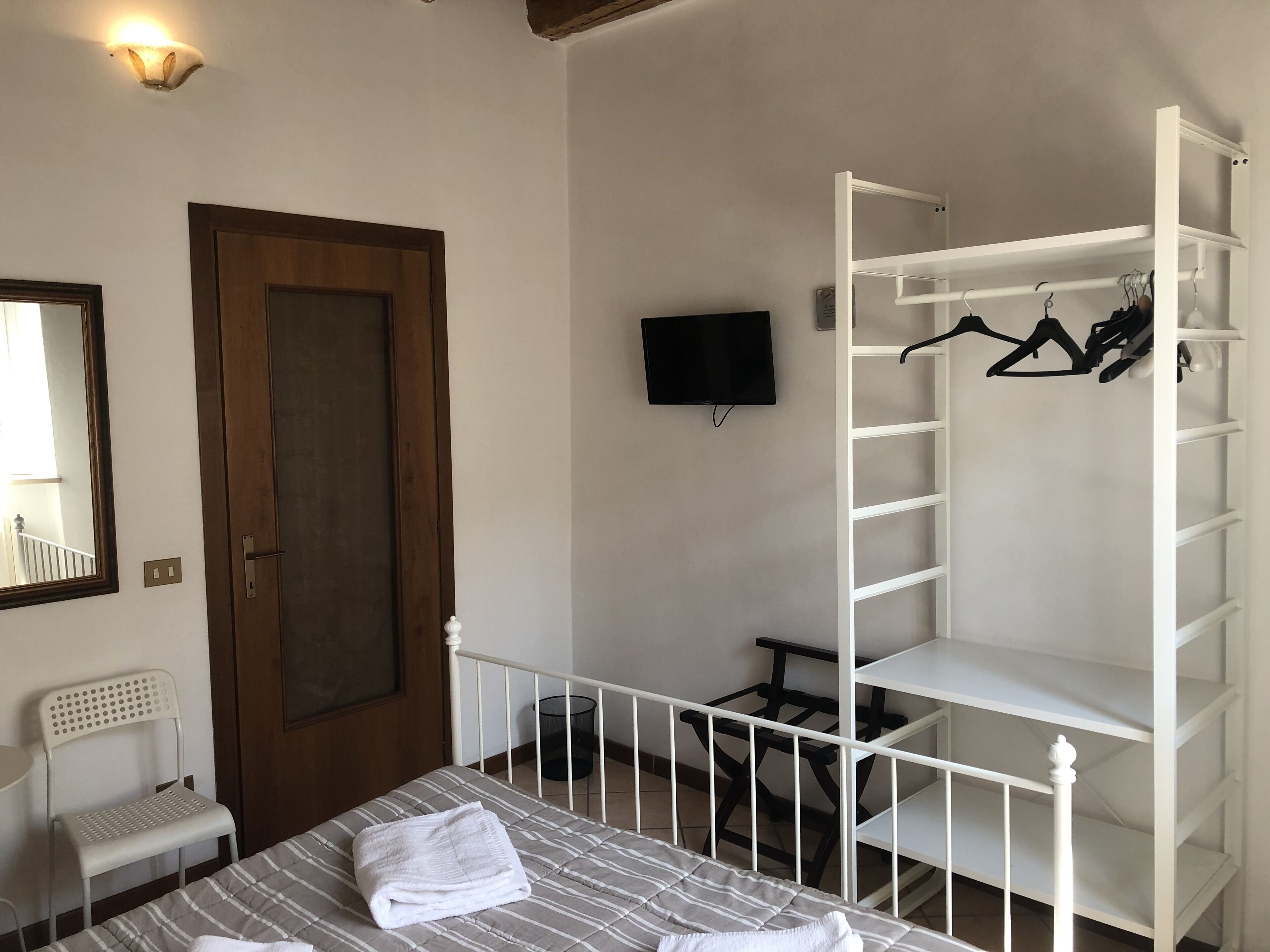 Ein Schlafzimmer mit einem Bett, einem Kleiderschrank, einem Fernseher und einem Sessel.