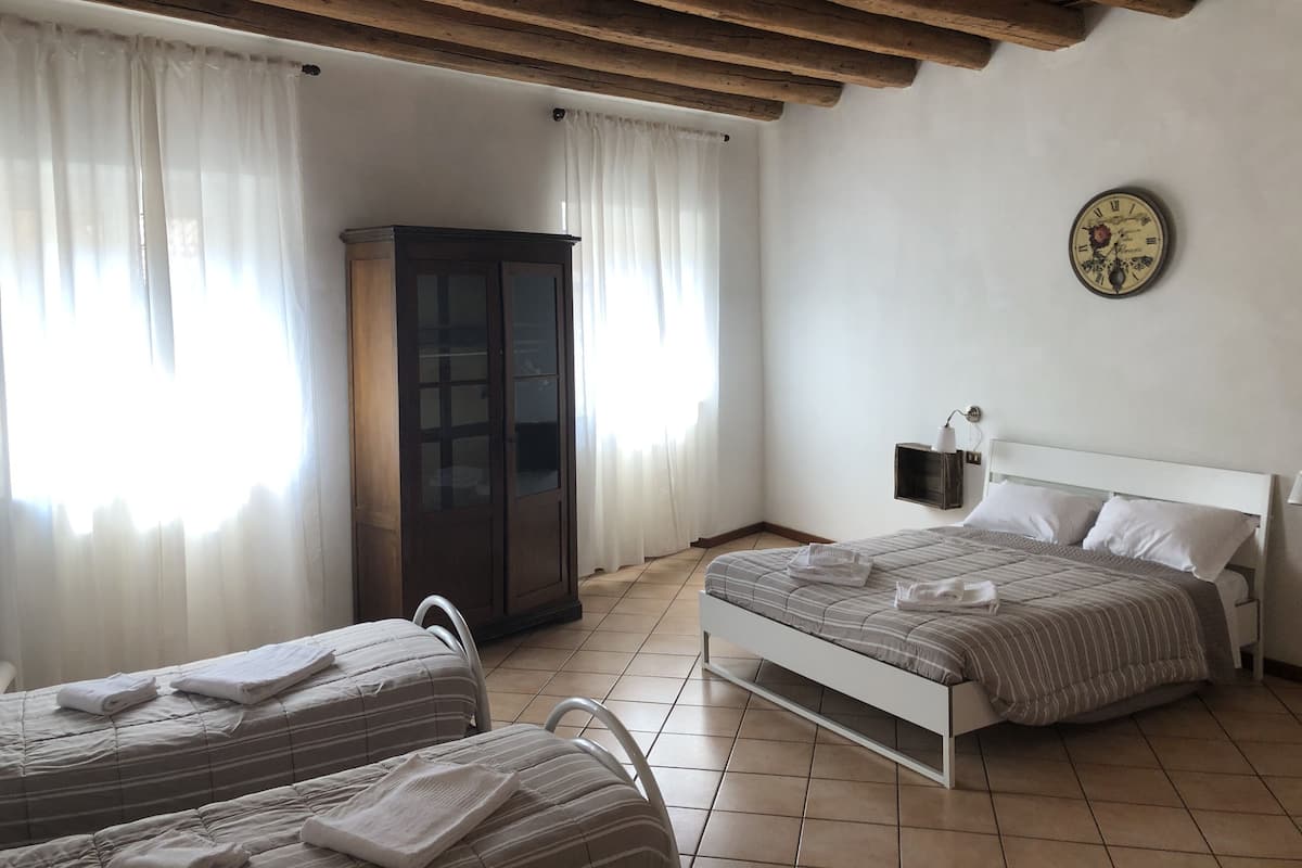 A bedroom with two beds, a wardrobe, a clock, and a window with curtains.