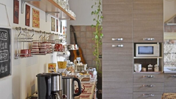 A kitchen with a coffee station, shelves with glassware, and a microwave. - Ai Leoni (Verona)