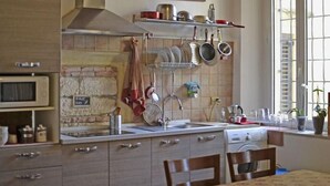 A kitchen with a stone backsplash, a hanging pot rack, and a sign reading "KITCHEN". - Ai Leoni (Verona)