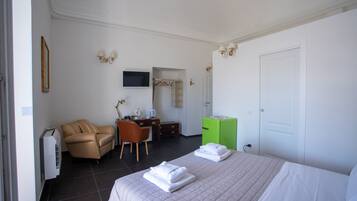 Una camera d'albergo con un letto, una sedia, una scrivania, una televisione e un armadio.