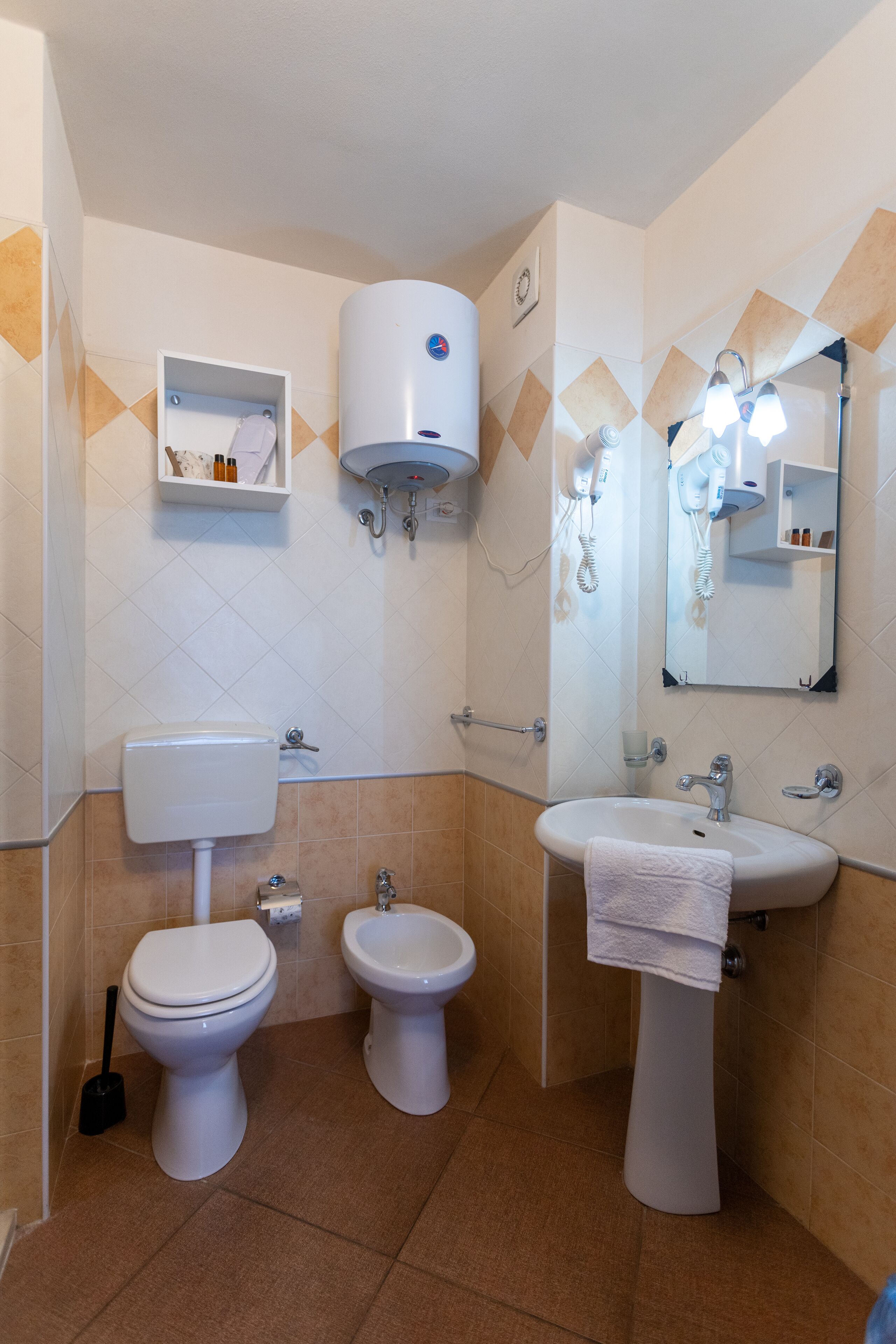 A bathroom with a toilet, bidet, and sink, equipped with a hairdryer and a mirror.