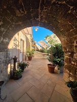Un patio al aire libre con paredes de piedra, plantas en macetas y mobiliario exterior.