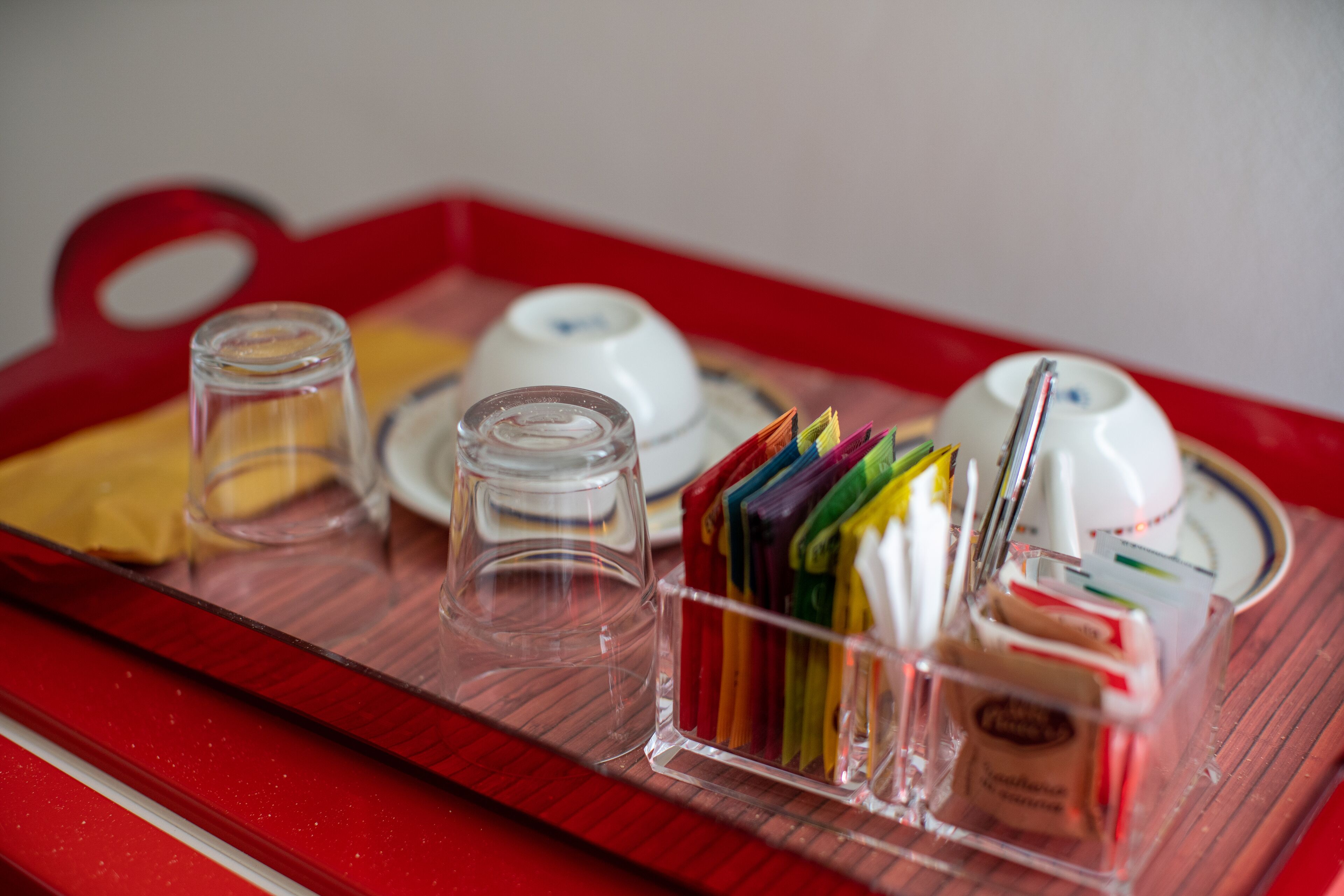 Una bandeja con tazas de té, vasos y una caja de bolsitas de té.