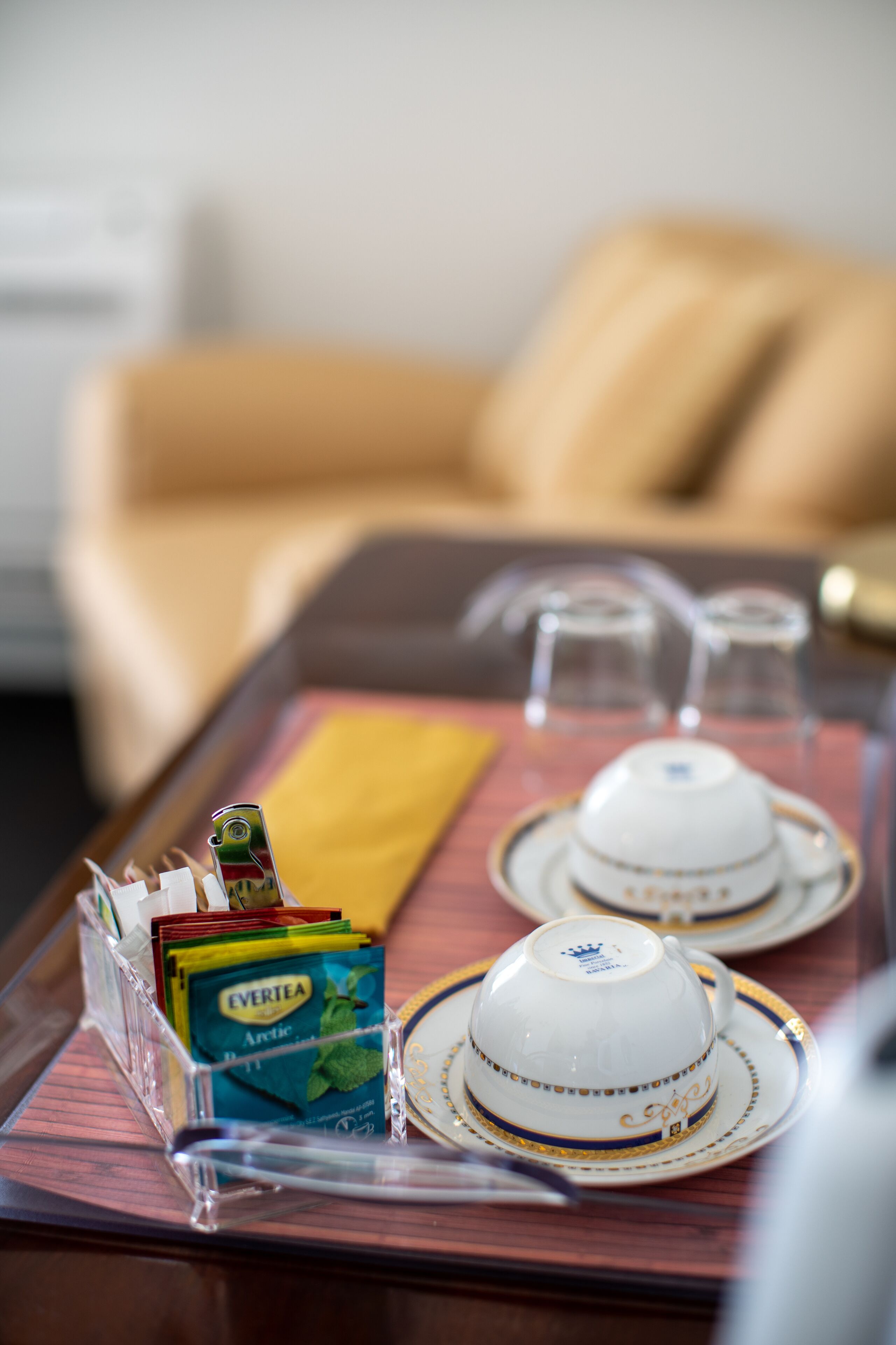 A tray with two white teacups and saucers, a yellow napkin, and a clear plastic container holding a pack of Evertea Arctic tea.