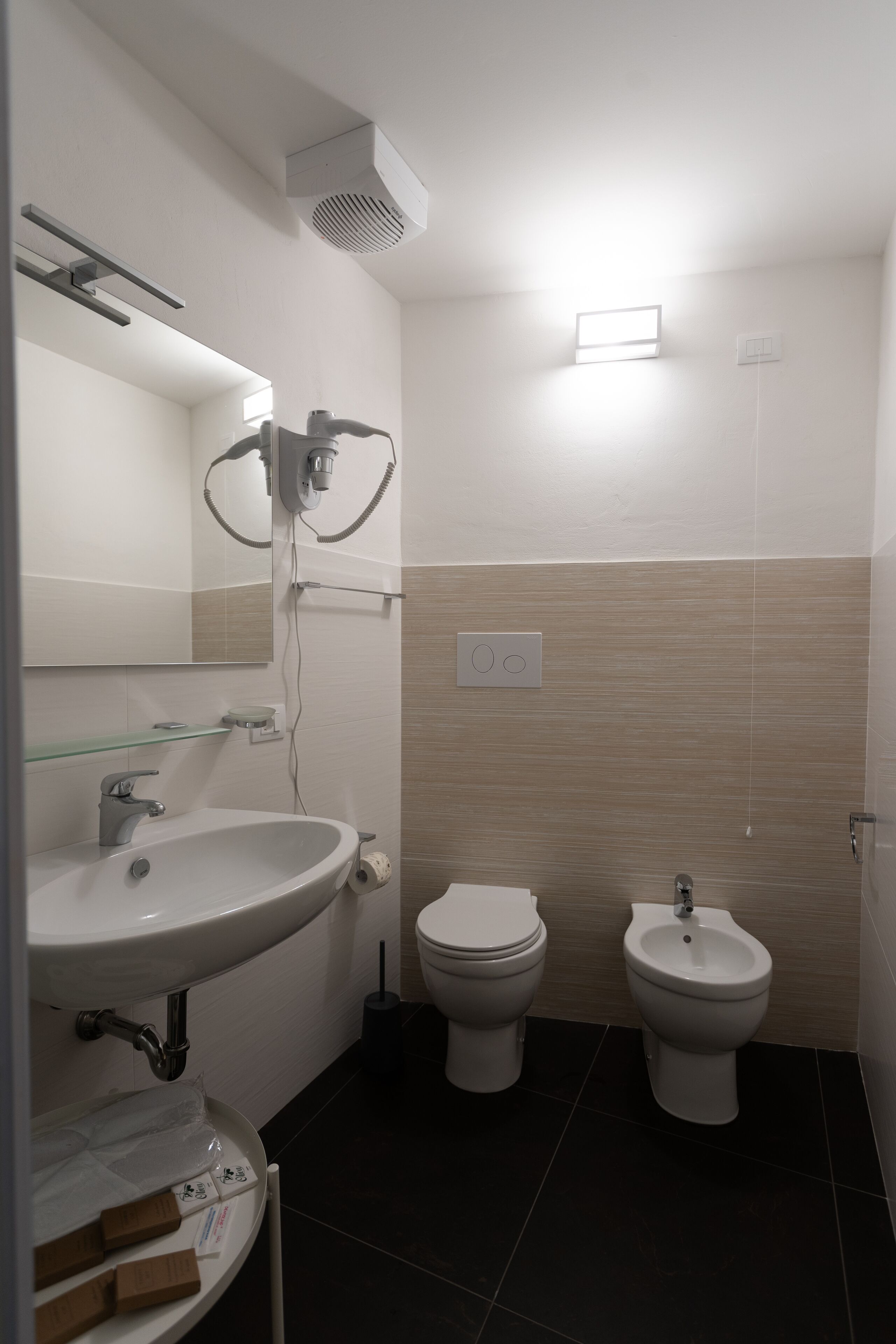 Une salle de bain moderne équipée d’un lavabo, de deux toilettes et d’un bidet.