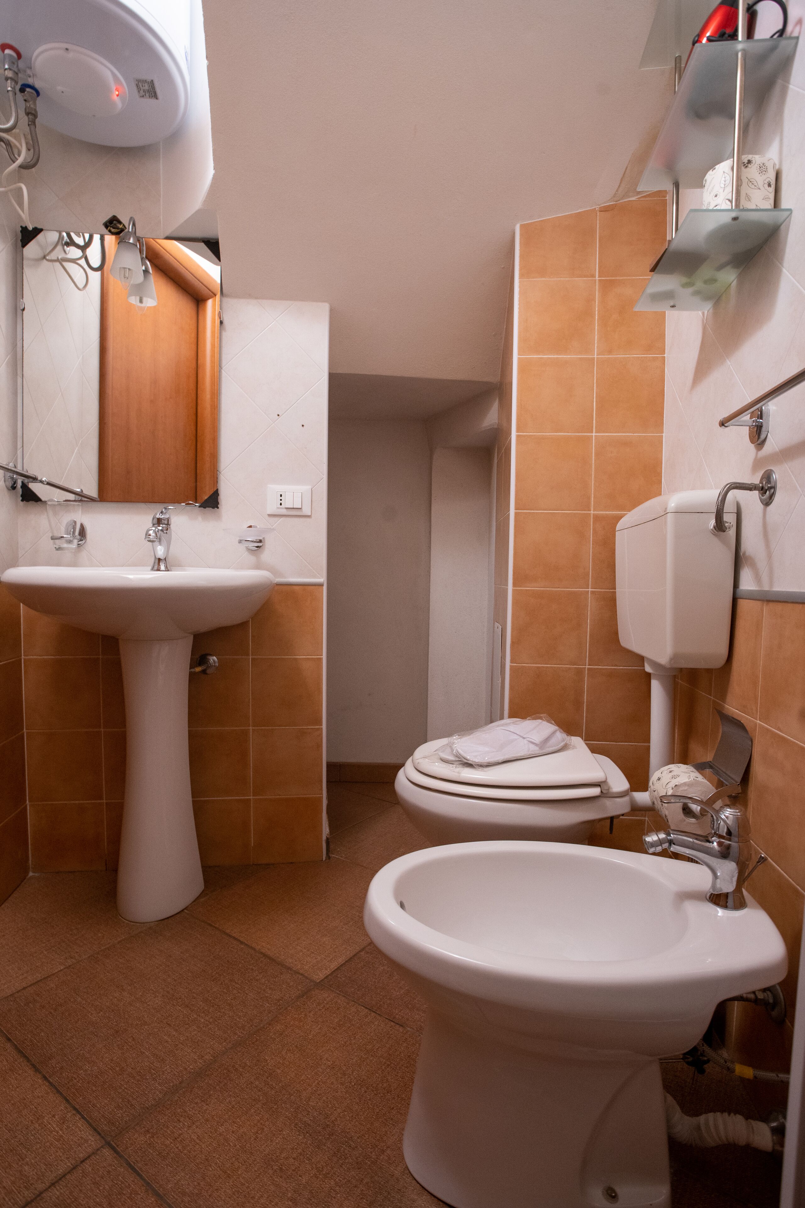 A bathroom with a pedestal sink, a toilet, and a bidet.