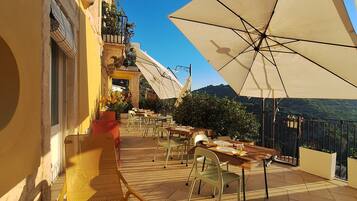An outdoor seating area with tables and chairs, umbrellas, and a view of the landscape.